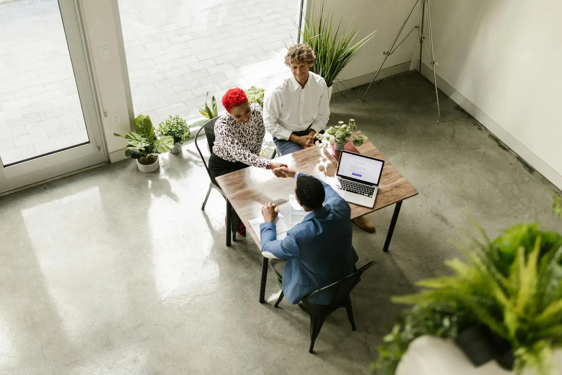 Three individuals seated at a table, each using a laptop, engaged in a collaborative work session.